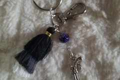 Sale retail: Porte clé avec pompon noir, gris et blanc révolver 